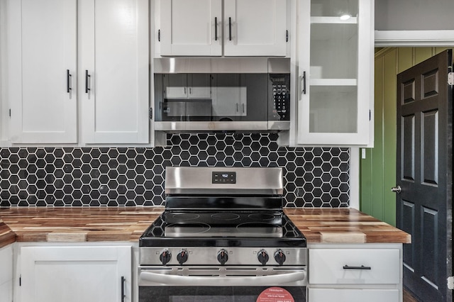 kitchen featuring white cabinetry, appliances with stainless steel finishes, wood counters, and decorative backsplash