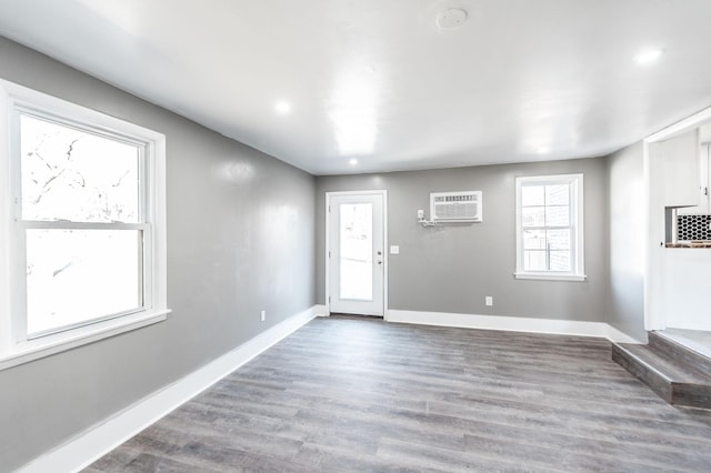 foyer entrance featuring hardwood / wood-style floors and a wall unit AC