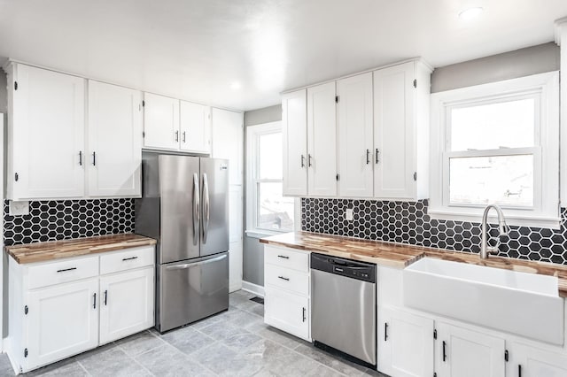 kitchen with wood counters, sink, white cabinets, decorative backsplash, and stainless steel appliances