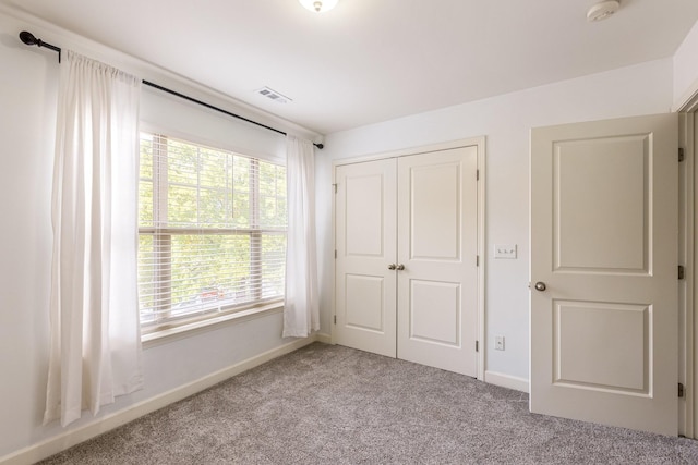 unfurnished bedroom with light colored carpet, a closet, and multiple windows