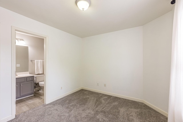 unfurnished bedroom with sink, light colored carpet, and ensuite bath