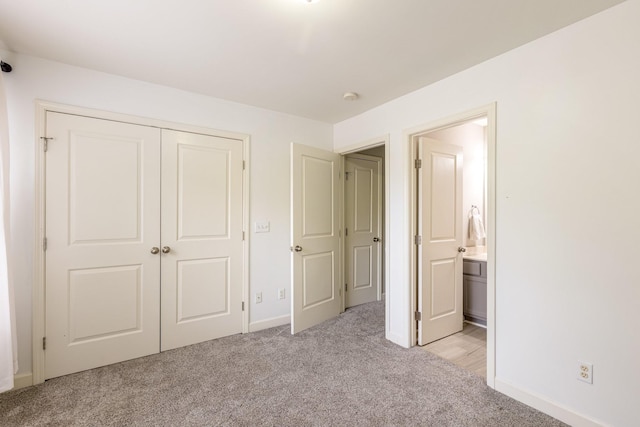 unfurnished bedroom featuring light carpet, connected bathroom, and a closet