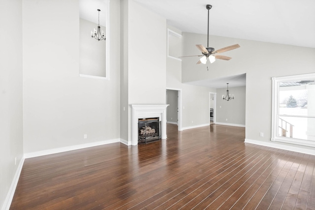 unfurnished living room featuring dark hardwood / wood-style flooring, ceiling fan with notable chandelier, and high vaulted ceiling