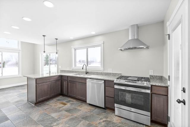 kitchen with wall chimney range hood, pendant lighting, kitchen peninsula, sink, and appliances with stainless steel finishes