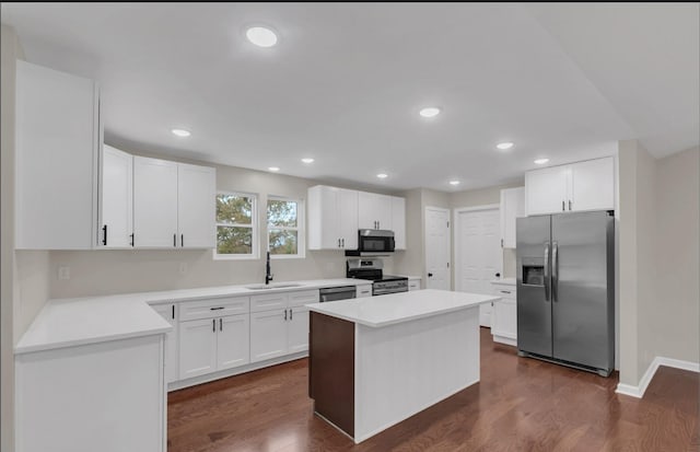 kitchen featuring appliances with stainless steel finishes, dark wood-type flooring, sink, a center island, and white cabinetry