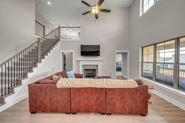 living room with a high ceiling, hardwood / wood-style flooring, and ceiling fan