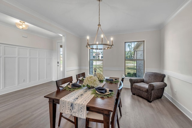 dining room with a chandelier, wood-type flooring, and ornamental molding