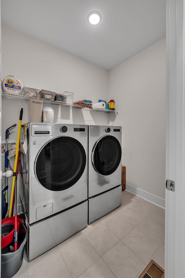 clothes washing area with washer and dryer and light tile patterned floors