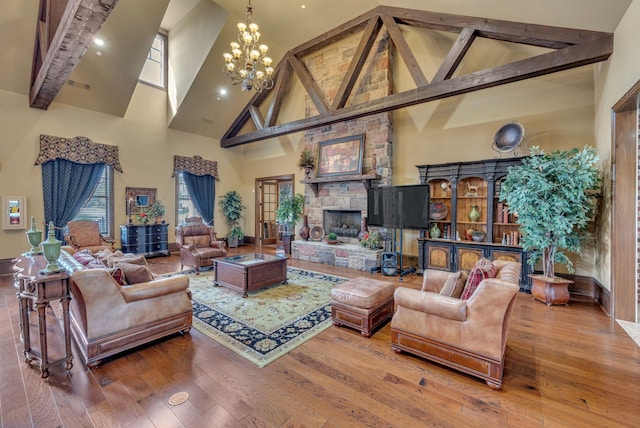 living room featuring wood-type flooring, an inviting chandelier, high vaulted ceiling, beamed ceiling, and a stone fireplace