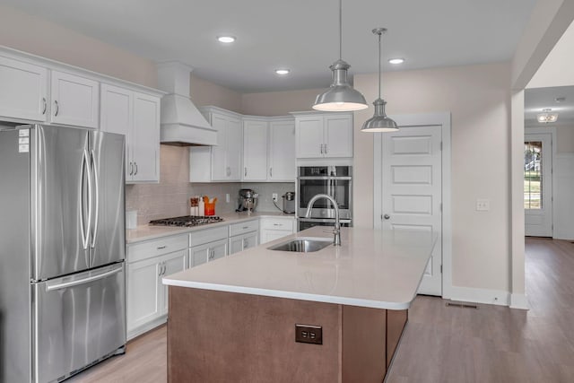 kitchen with sink, white cabinets, stainless steel appliances, and custom range hood