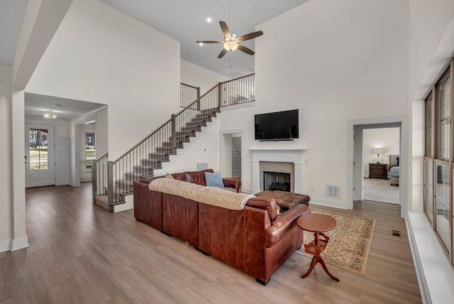 living room featuring ceiling fan, a towering ceiling, and wood-type flooring