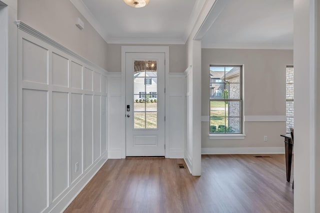 doorway featuring light hardwood / wood-style flooring, plenty of natural light, and crown molding