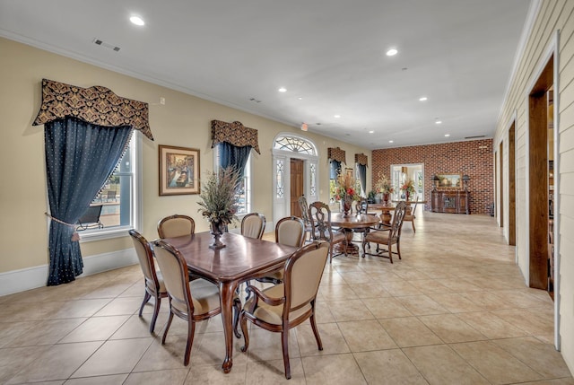 dining space featuring light tile patterned flooring, crown molding, and brick wall