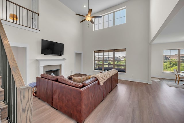 living room featuring ceiling fan, light hardwood / wood-style floors, and a high ceiling