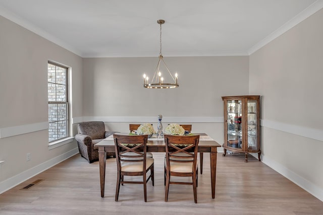 dining space with light hardwood / wood-style flooring, a chandelier, and ornamental molding