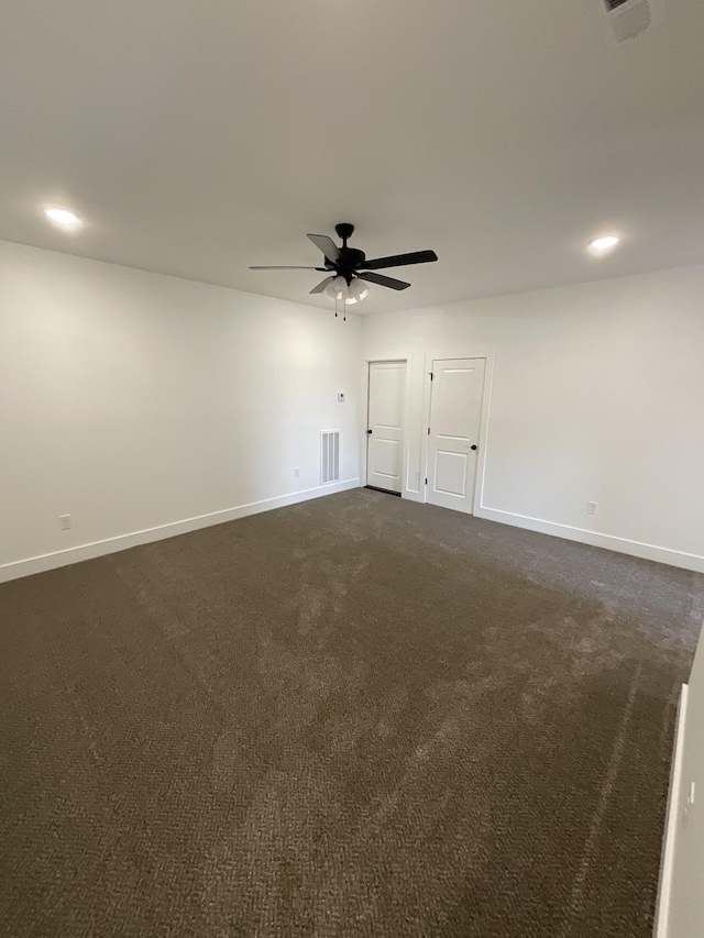 spare room with ceiling fan and dark carpet