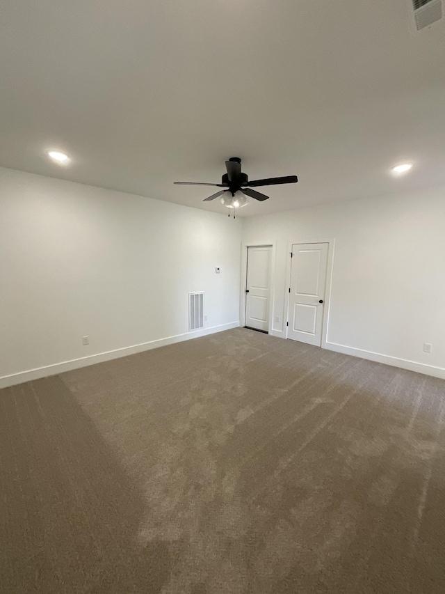 unfurnished room with dark colored carpet and ceiling fan