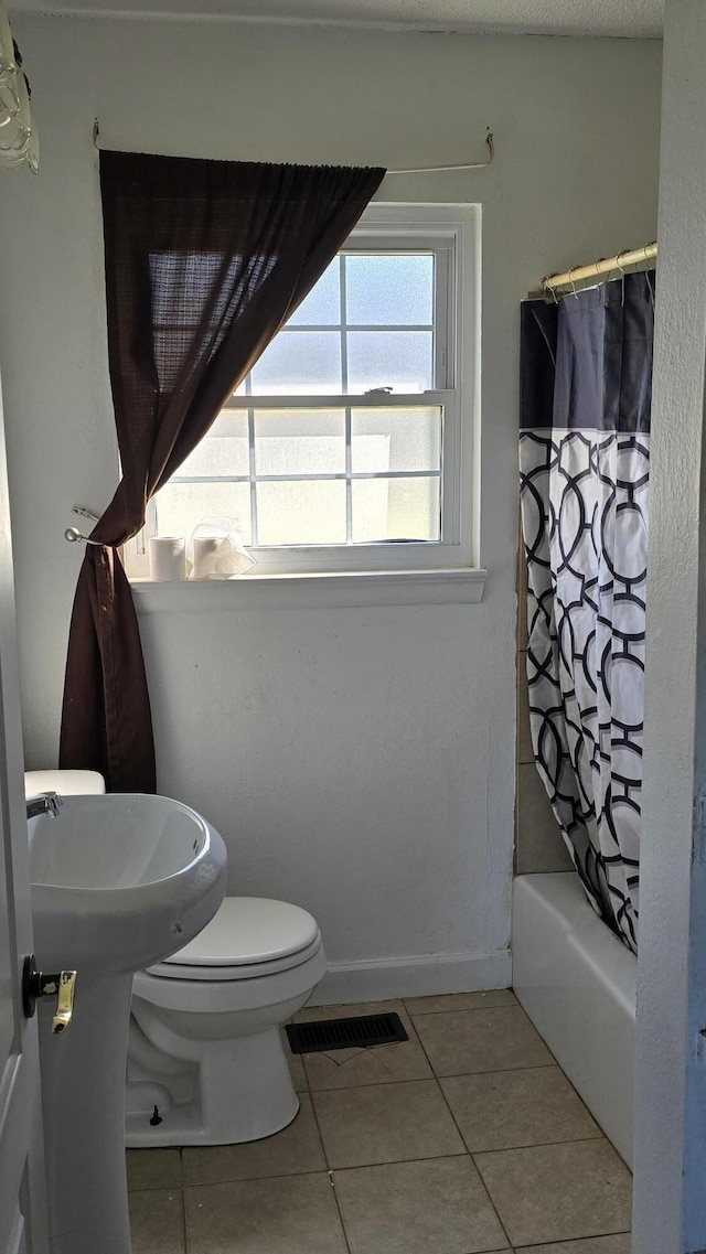 bathroom featuring tile patterned floors, toilet, and shower / tub combo