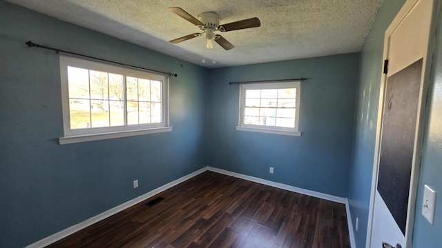 unfurnished room with plenty of natural light, dark wood-type flooring, and a textured ceiling