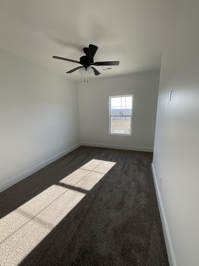 spare room with dark colored carpet and ceiling fan