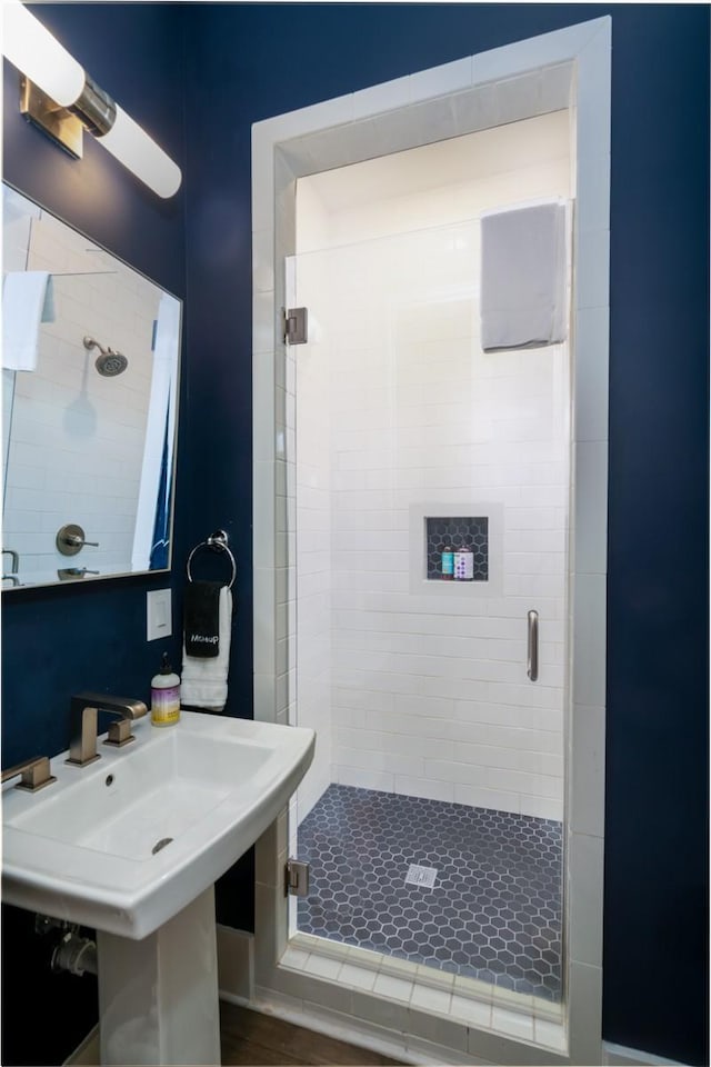 bathroom featuring a shower with shower door and sink