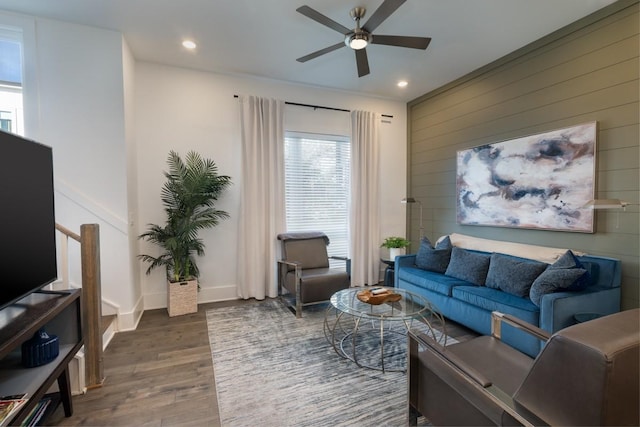 living room featuring wood walls, ceiling fan, and dark wood-type flooring