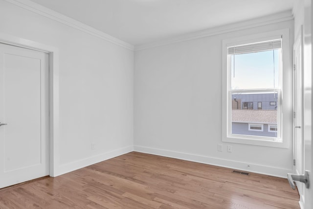 empty room featuring visible vents, baseboards, light wood-style floors, and ornamental molding