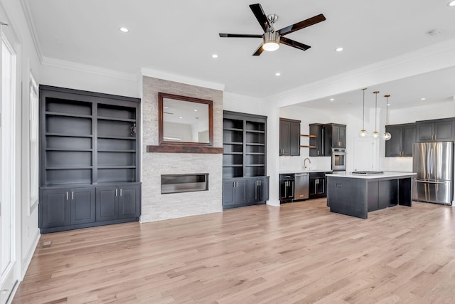 kitchen with open shelves, open floor plan, light countertops, appliances with stainless steel finishes, and a sink