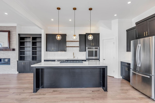 kitchen with light wood-style flooring, appliances with stainless steel finishes, a center island, and light countertops