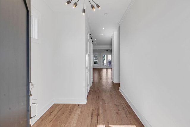 hall with baseboards, light wood finished floors, recessed lighting, ornamental molding, and a barn door