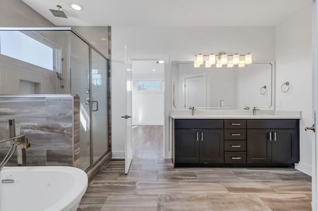 bathroom with a shower stall, baseboards, a freestanding bath, double vanity, and a sink