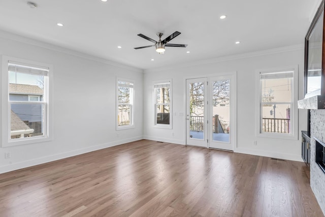 unfurnished living room featuring a glass covered fireplace, crown molding, and wood finished floors