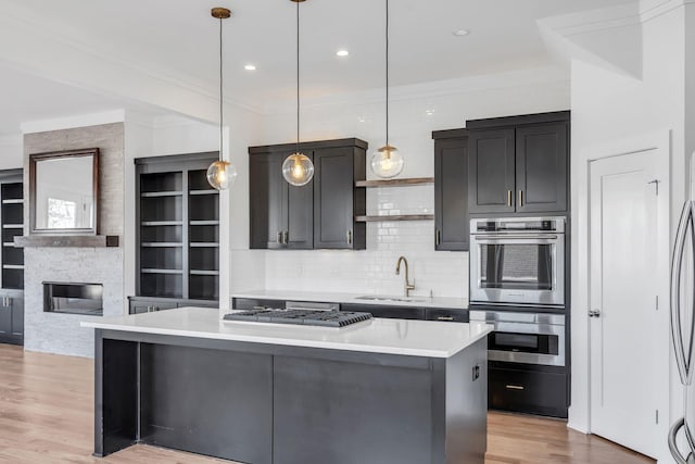 kitchen with light wood finished floors, a center island, light countertops, stainless steel double oven, and a sink