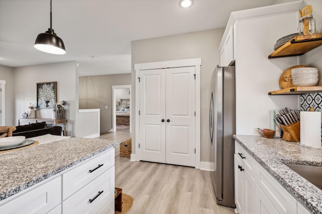 kitchen with stainless steel fridge, white cabinetry, pendant lighting, and light wood-type flooring