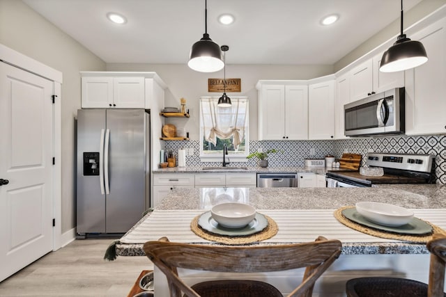 kitchen featuring decorative light fixtures, white cabinetry, sink, and appliances with stainless steel finishes