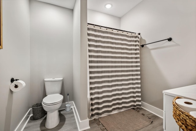 bathroom with hardwood / wood-style floors, toilet, and a shower with shower curtain