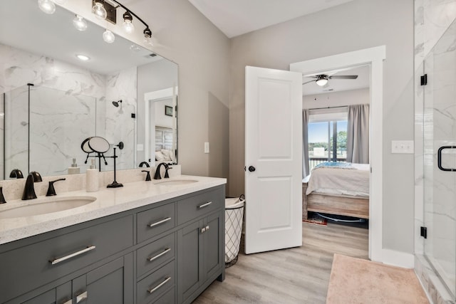 bathroom with hardwood / wood-style flooring, ceiling fan, a shower with shower door, and vanity