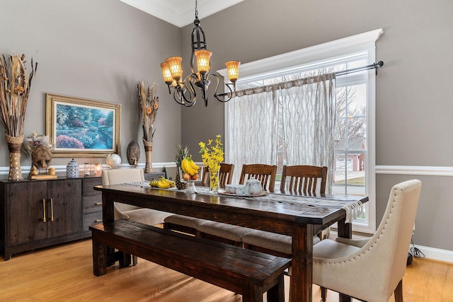 dining area with a wealth of natural light, crown molding, light hardwood / wood-style floors, and an inviting chandelier