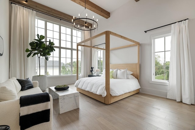 bedroom featuring beamed ceiling, light hardwood / wood-style floors, and an inviting chandelier