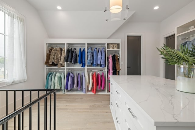 spacious closet with light hardwood / wood-style floors and lofted ceiling