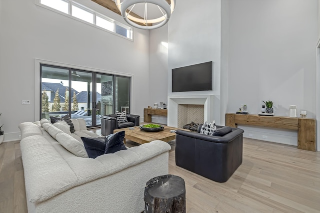 living room featuring wood-type flooring, an inviting chandelier, and a high ceiling