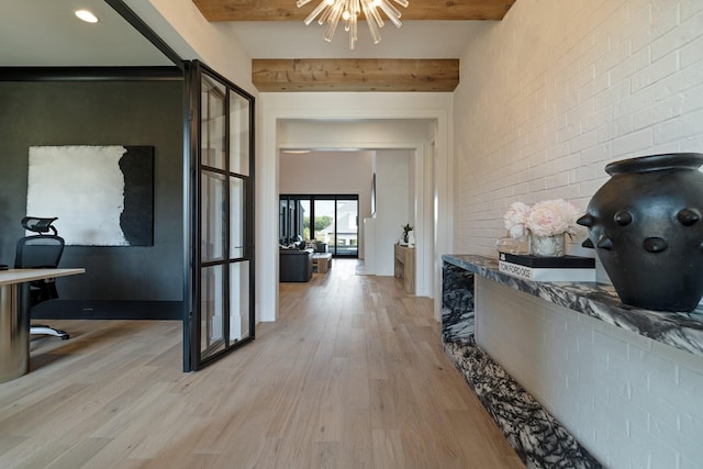 hall with beamed ceiling, light hardwood / wood-style flooring, a notable chandelier, and brick wall