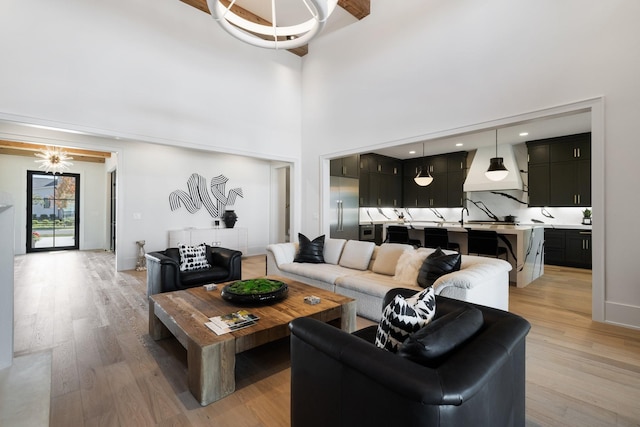 living room with light wood-type flooring, sink, and a towering ceiling