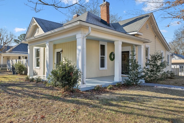 view of side of home featuring a porch and a lawn