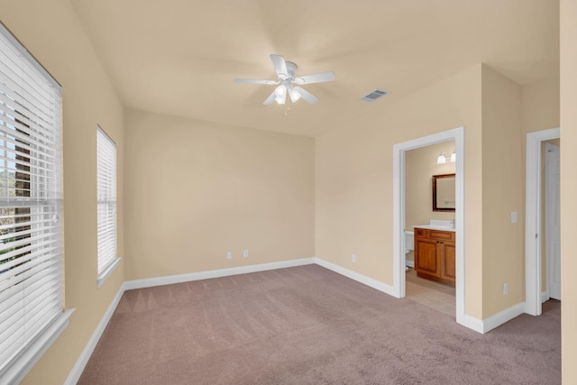 unfurnished bedroom featuring ensuite bath, ceiling fan, and light colored carpet