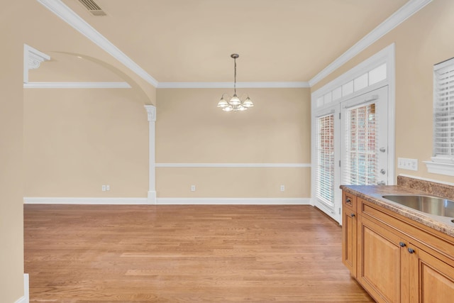 unfurnished dining area with a chandelier, light hardwood / wood-style floors, ornamental molding, and sink