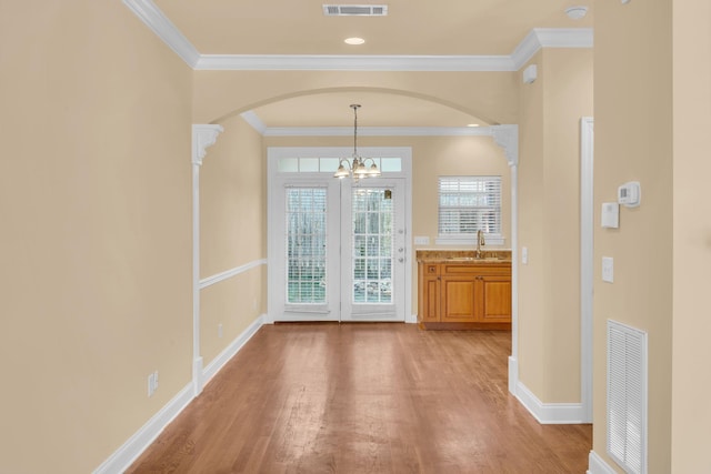 unfurnished dining area featuring light hardwood / wood-style floors, a notable chandelier, ornamental molding, and sink