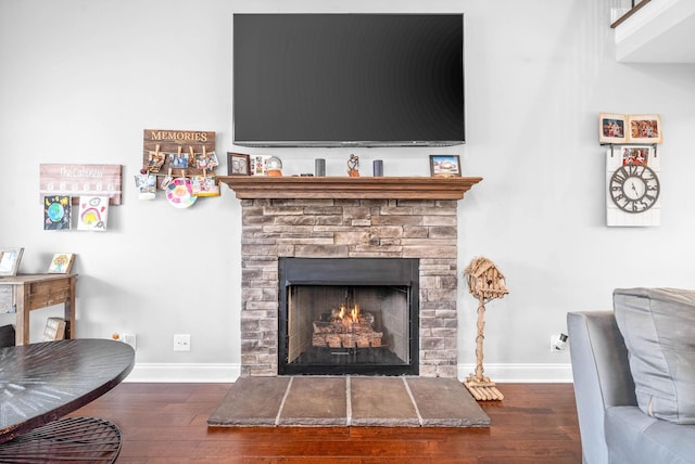 living room featuring dark wood-type flooring and a stone fireplace