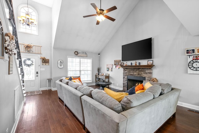 living room with ceiling fan with notable chandelier, a stone fireplace, high vaulted ceiling, and dark hardwood / wood-style floors