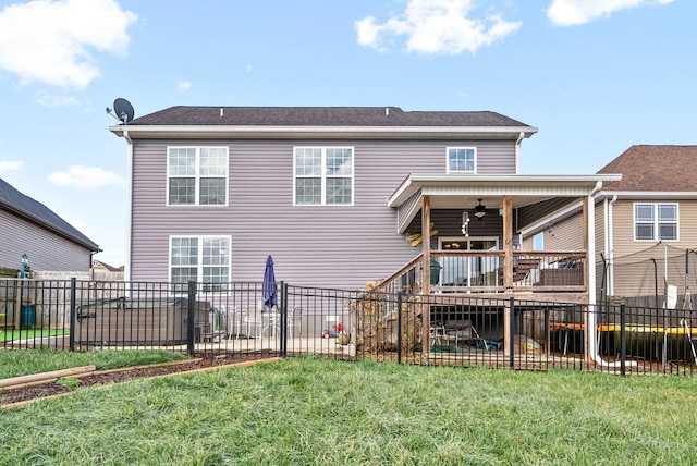 rear view of property with ceiling fan and a yard